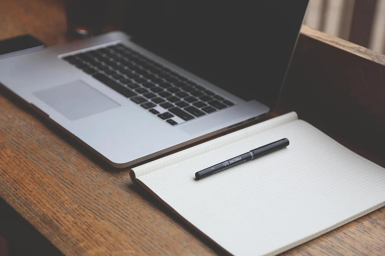 Aufgeräumter Arbeitsplatz mit Laptop, Notizbuch und Kaffeetasse – Produktivität durch Desktop-Ordnung