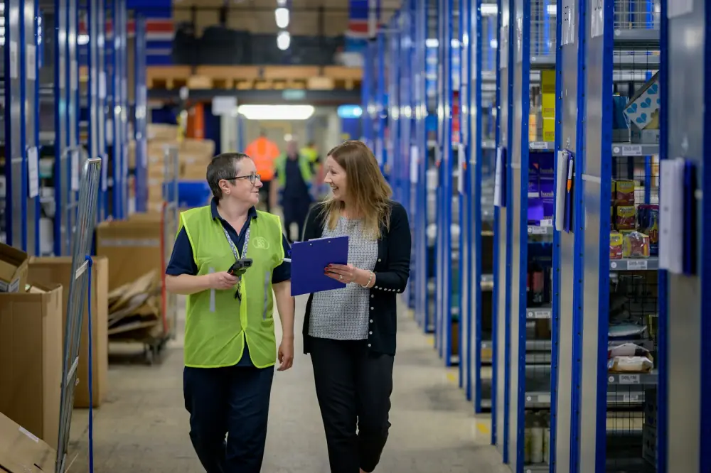 Logistik-Manager und Lagermitarbeiterin besprechen Bestandsdaten am Tablet im Hochregallager