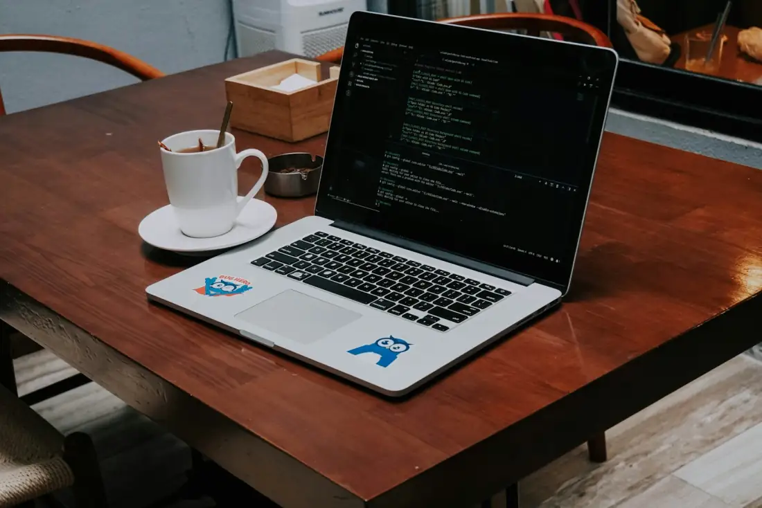 Notebook mit Entwickler-Umgebung auf Holztisch — moderne Cloud-Arbeitsplätze ersetzen in vielen KMU den eigenen Server