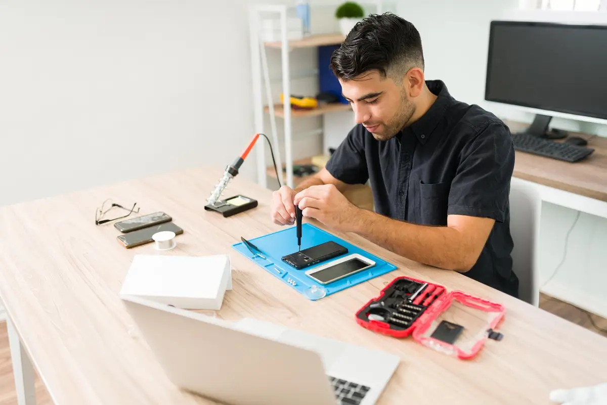 IT-Techniker in einer Werkstatt arbeitet an einem Gerät — Symbolbild für Hardware-Instandhaltung