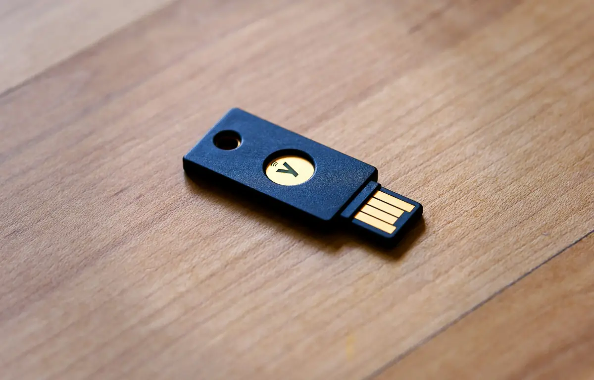 Hardware-Sicherheitsschlüssel (YubiKey-ähnlich) auf Holzoberfläche — phishing-resistente FIDO2-Authentifizierung