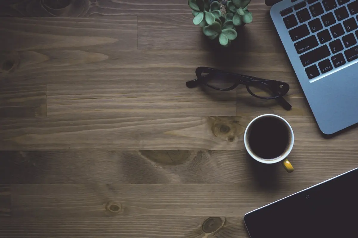 Workspace mit Laptop, Kaffee und Brille — der Mbit/s-Bedarf bei Teams und Cloud hängt von Use-Cases ab
