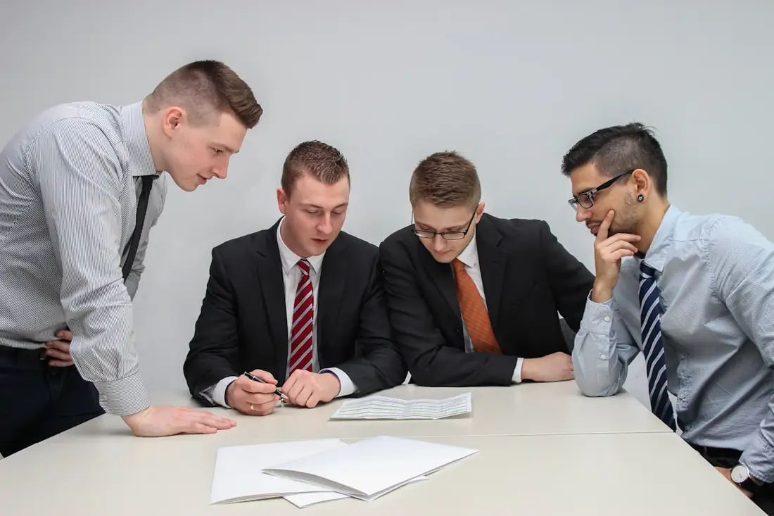 IT-Firma Beratung: Vier Kollegen besprechen gemeinsam einen Plan auf einem Blatt Papier am Konferenztisch — typisches Erstgespräch mit dem IT-Dienstleister.
