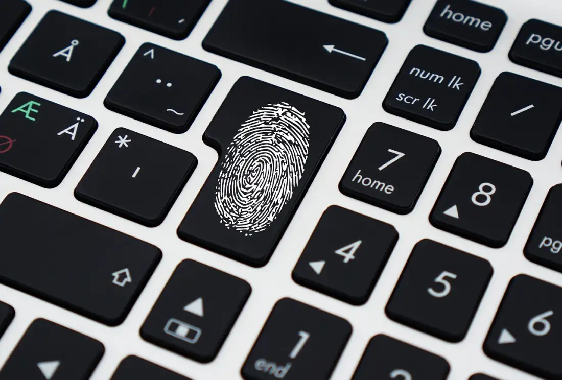 Hand am Laptop mit Passwort-Eingabe — Multi-Faktor-Authentifizierung schützt vor Account-Übernahme