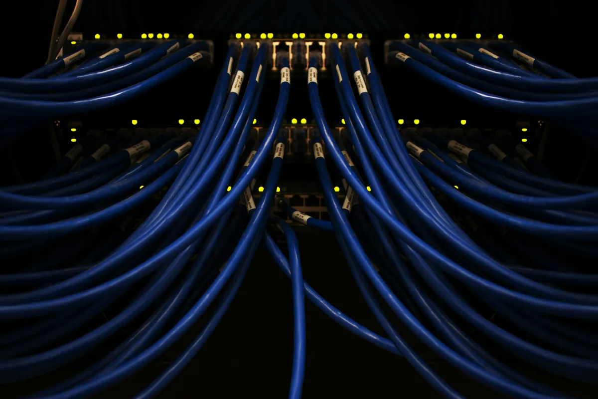 Patchpanel mit blauen Ethernet-Patchkabeln und LED-Status-Anzeige im Serverschrank