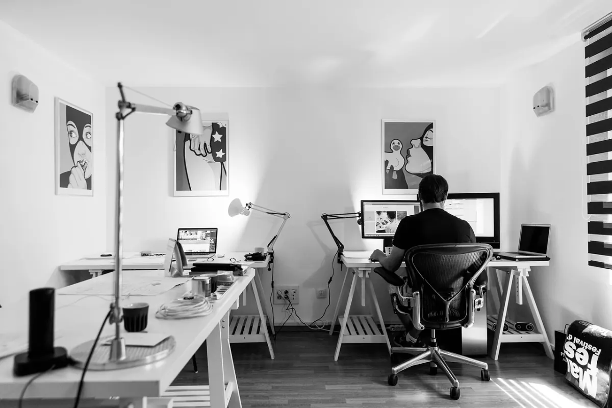 Zwei Bildschirme am Arbeitsplatz — Designerin arbeitet mit Dual-Monitor-Setup